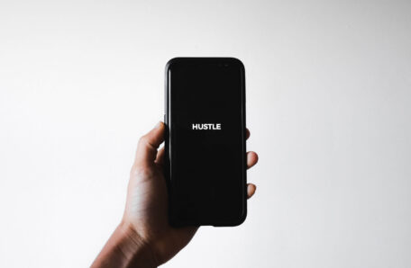 Man holding phone with word: HUSTLE