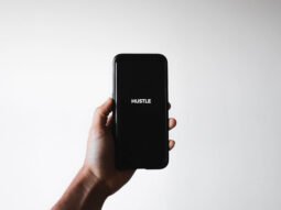 Man holding phone with word: HUSTLE